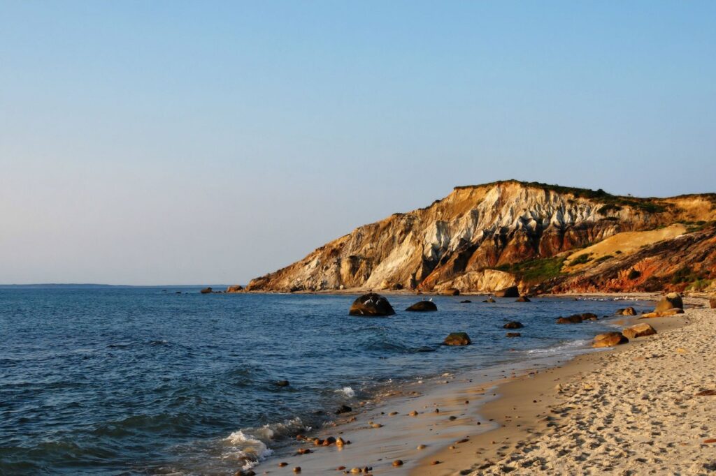 Layered red, orange and white clay cliffs above a boulder-strewn beach at Aquinnah on Martha's Vineyard