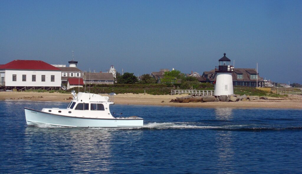 Brant Point Light at the mouth of Nantucket Harbor with a white lobster boat passing in front
