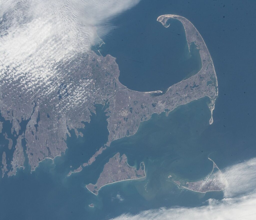 Astronaut photograph of Cape Cod curling into the Atlantic, with Cape Cod Bay inside the curve and Martha's Vineyard and Nantucket to the south