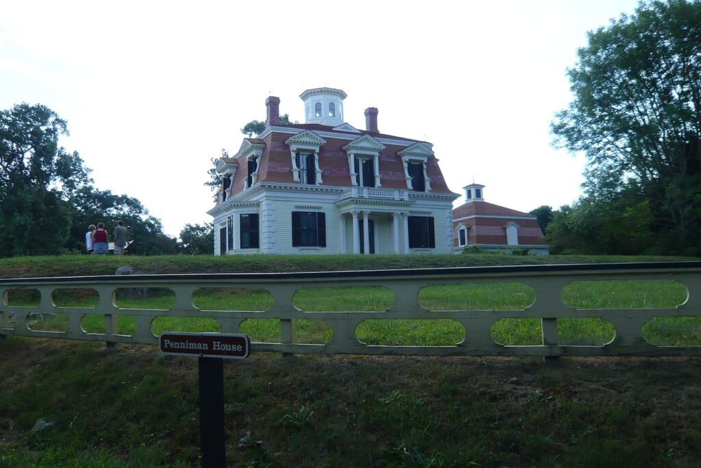 The white Second Empire-style Captain Edward Penniman House with its mansard roof and cupola, seen across a lawn