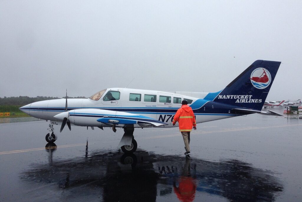 A small twin-engine Cessna in Nantucket Airlines colors parked on a wet ramp at Provincetown Municipal Airport