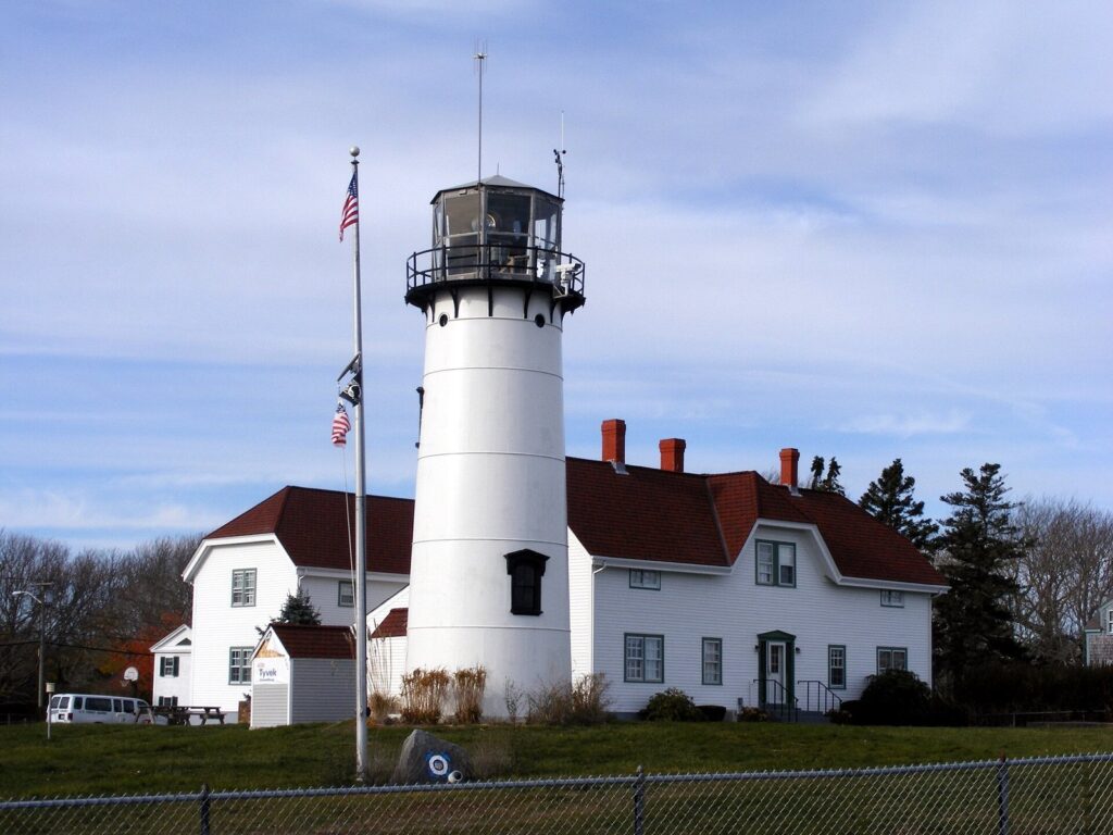 Chatham Light's white tower beside the red-roofed keeper's house and a flagpole
