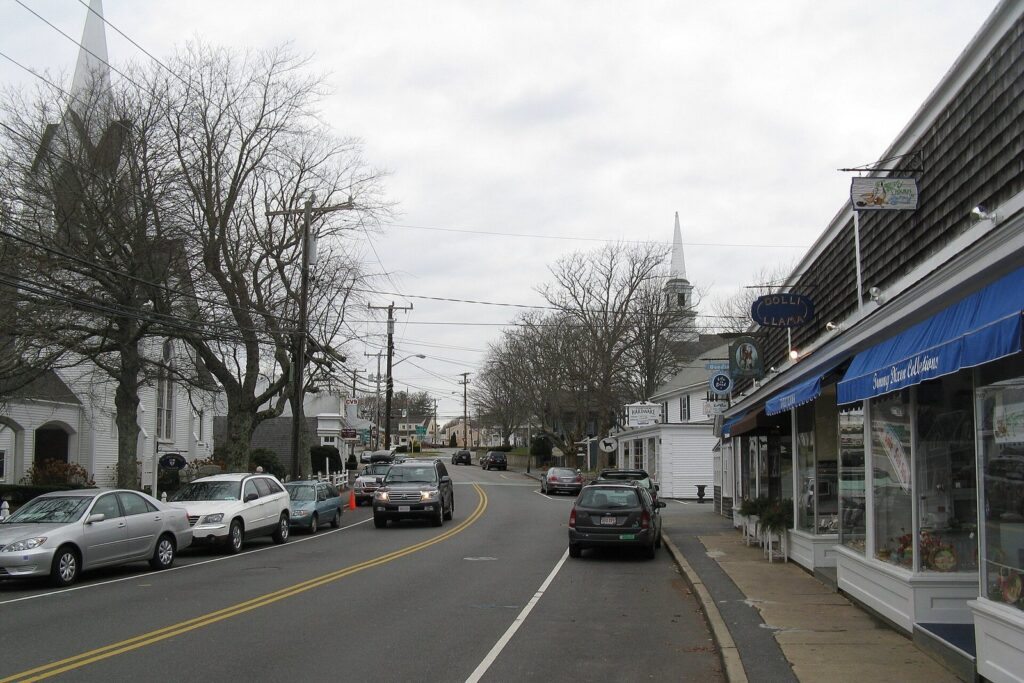 Shops with blue awnings along Main Street in Chatham, with white church steeples beyond