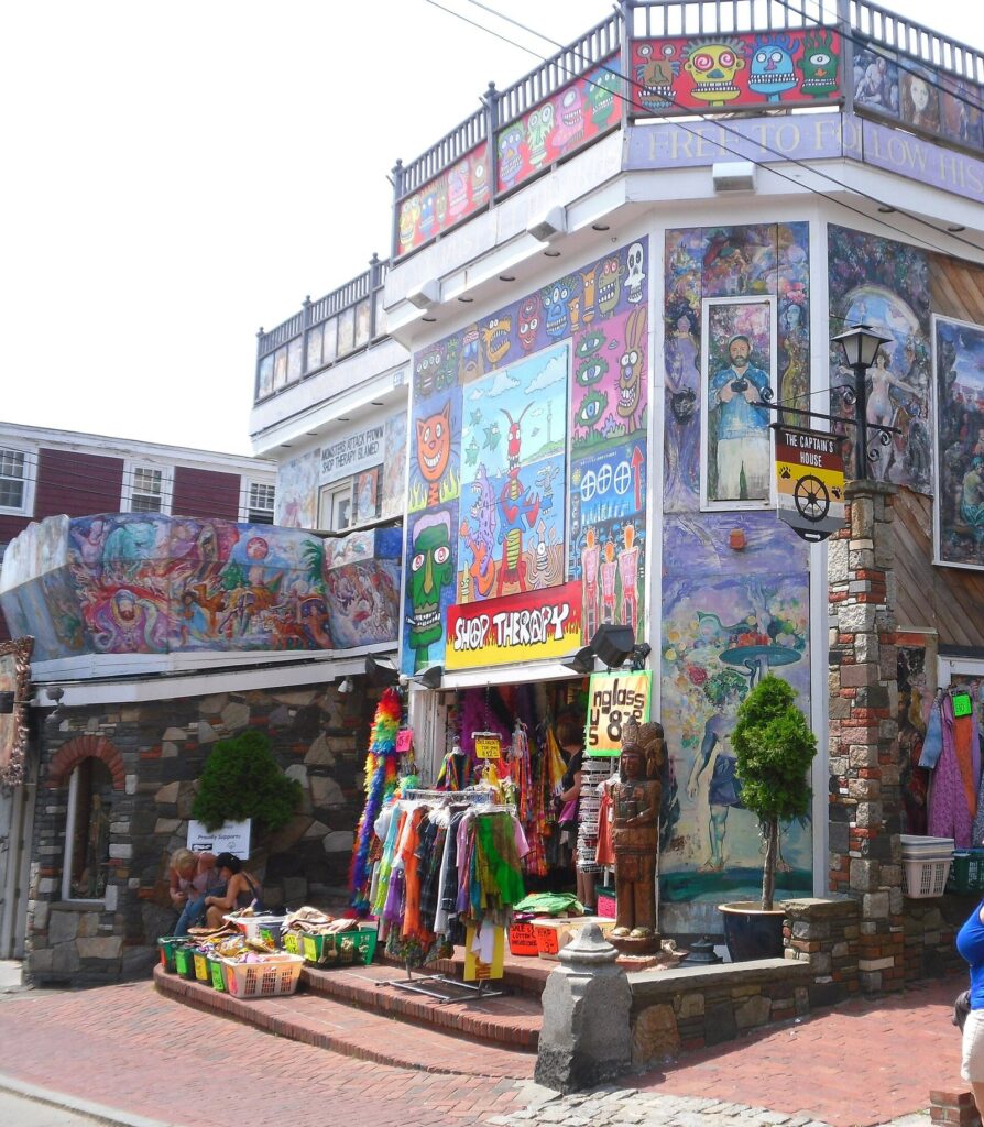 A shop on Commercial Street in Provincetown covered in colorful painted murals, with clothes and goods displayed outside