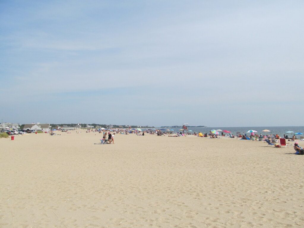 Umbrellas and swimmers along the wide sand of Craigville Beach on Nantucket Sound