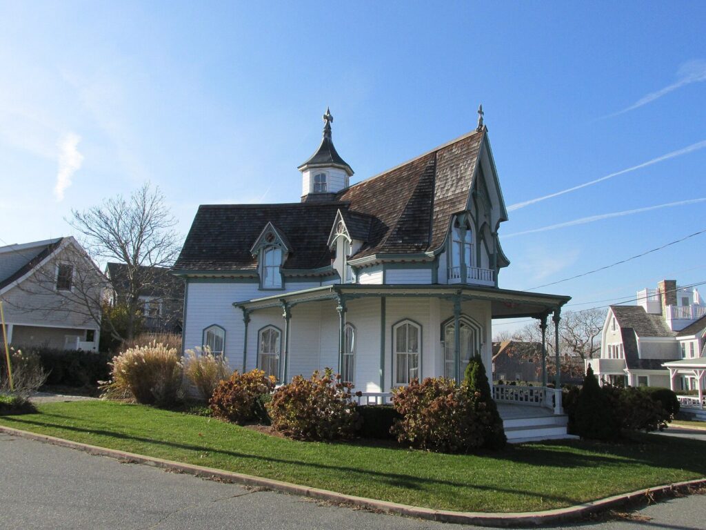 A white Gothic Revival cottage with a cupola and wraparound porch in Falmouth Heights