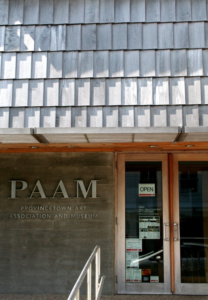 The glass entrance doors of the Provincetown Art Association and Museum under its name in raised letters on a concrete wall