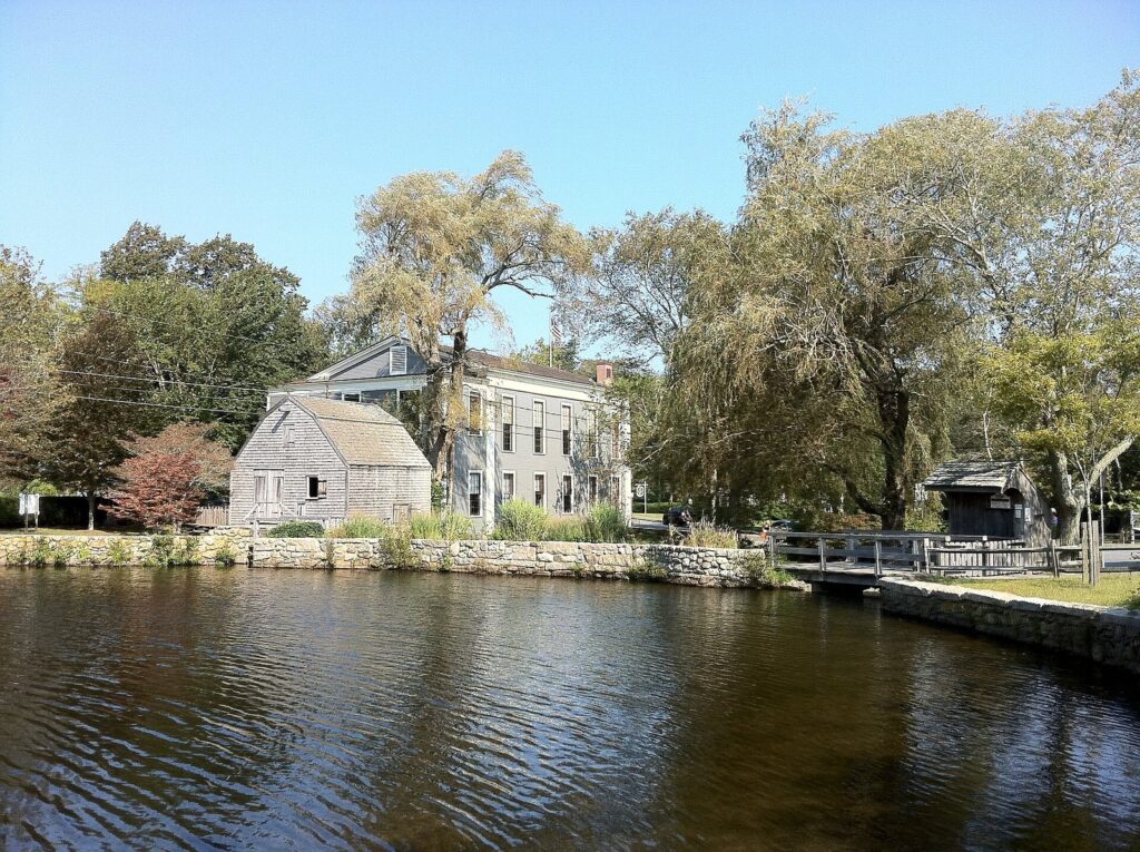 Shawme Pond in Sandwich with the shingled Dexter Grist Mill and old houses behind it