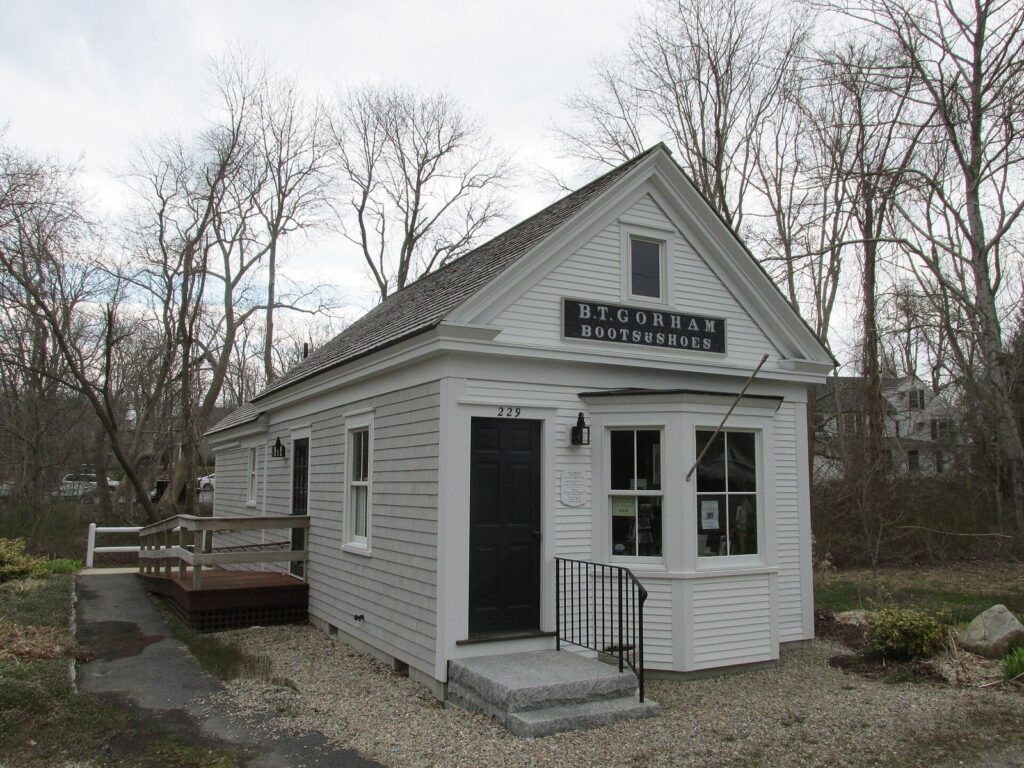 A small white 19th-century shop building labeled B.T. Gorham Boots and Shoes in Yarmouth Port